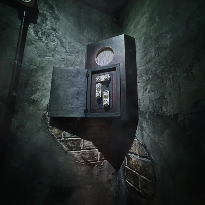 Secret wall safe with mechanical gear puzzle revealed behind cracked wall in escape room